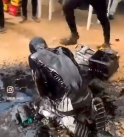 Auto mechanic apprentice drenched with dirty engine oil to celebrate his graduation